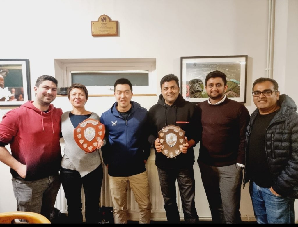 Headstone Tennis Club members holding two winter league shields in the clubhouse